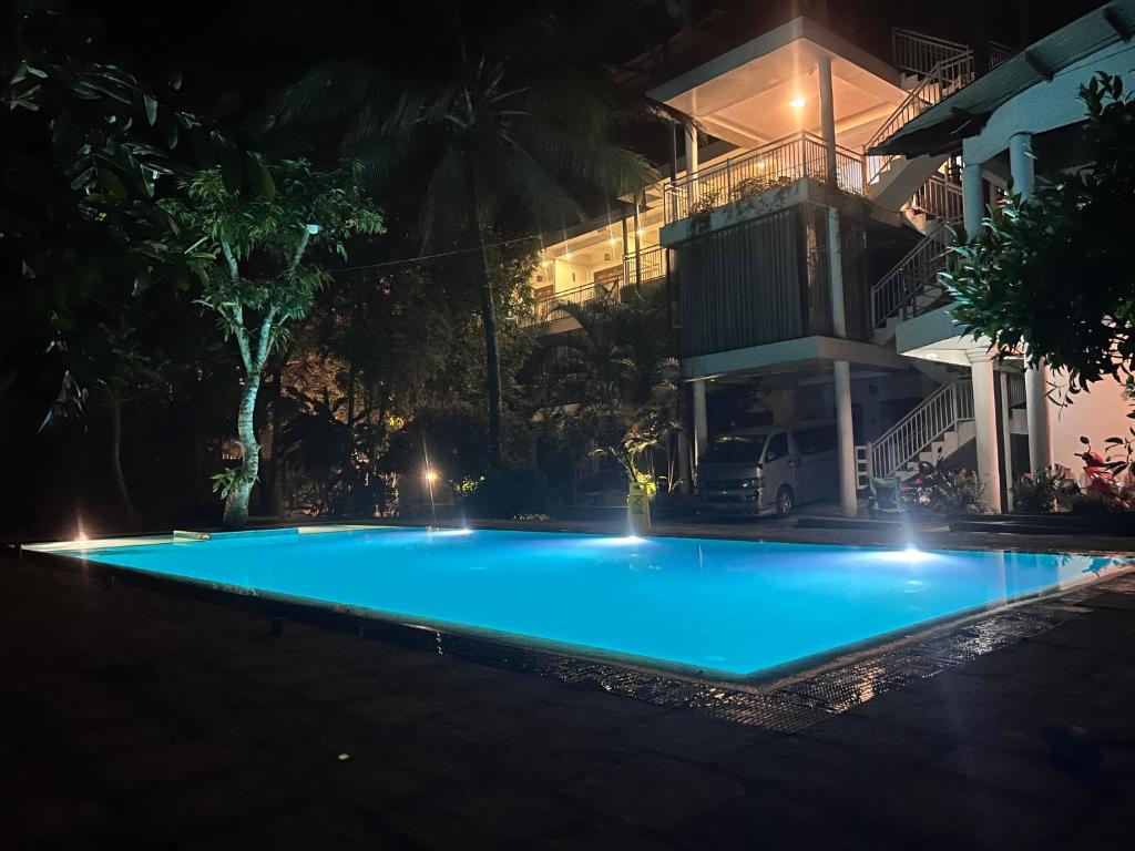 a large blue swimming pool in front of a building at night at French Garden Kandy in Kandy