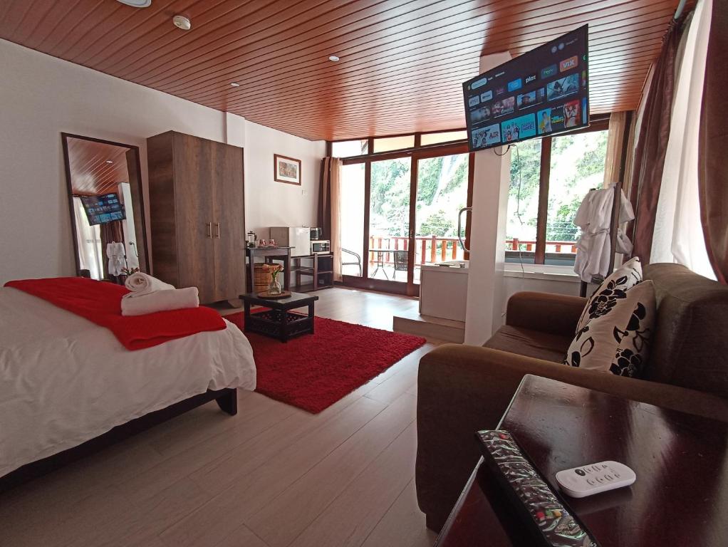 a bedroom with a bed and a living room with a couch at Posada J in Baños