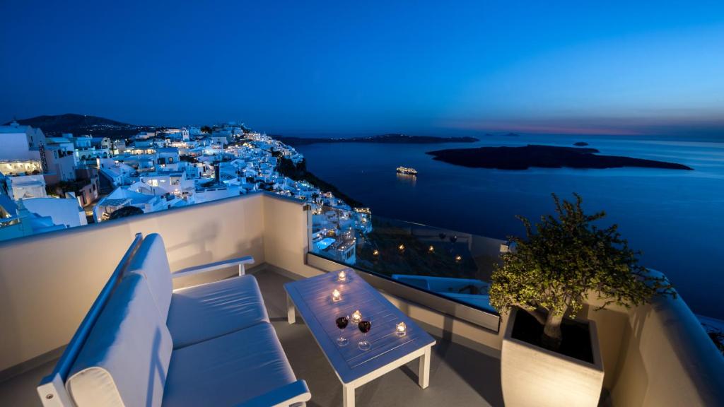 Un balcón con muebles azules y vistas al océano. en Damigos Caldera World, en Firostefani