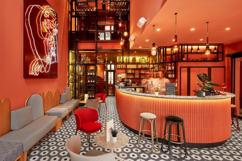 a bar in a restaurant with red walls and chairs at Hotel De Cambis in Avignon