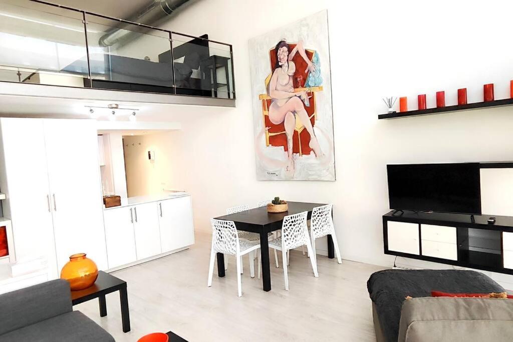 ein Wohnzimmer mit einem Tisch und einer Küche in der Unterkunft Fantástico Loft de Diseño en Alcalá de Henares - Madrid in Alcalá de Henares