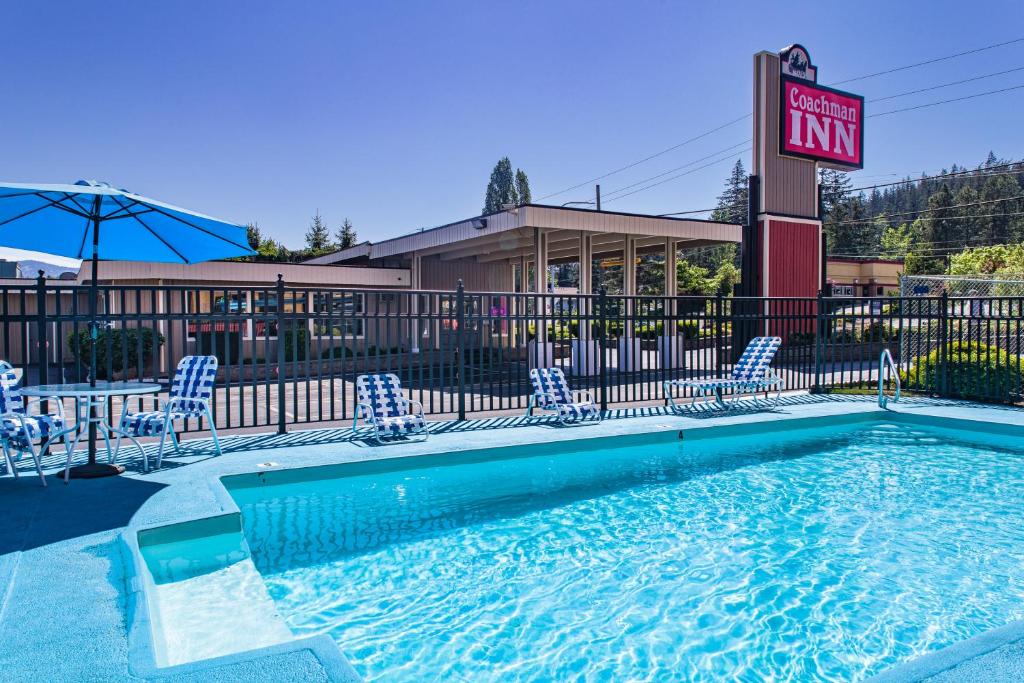a swimming pool at a hotel with chairs and a sign at Coachman Inn in Bellingham