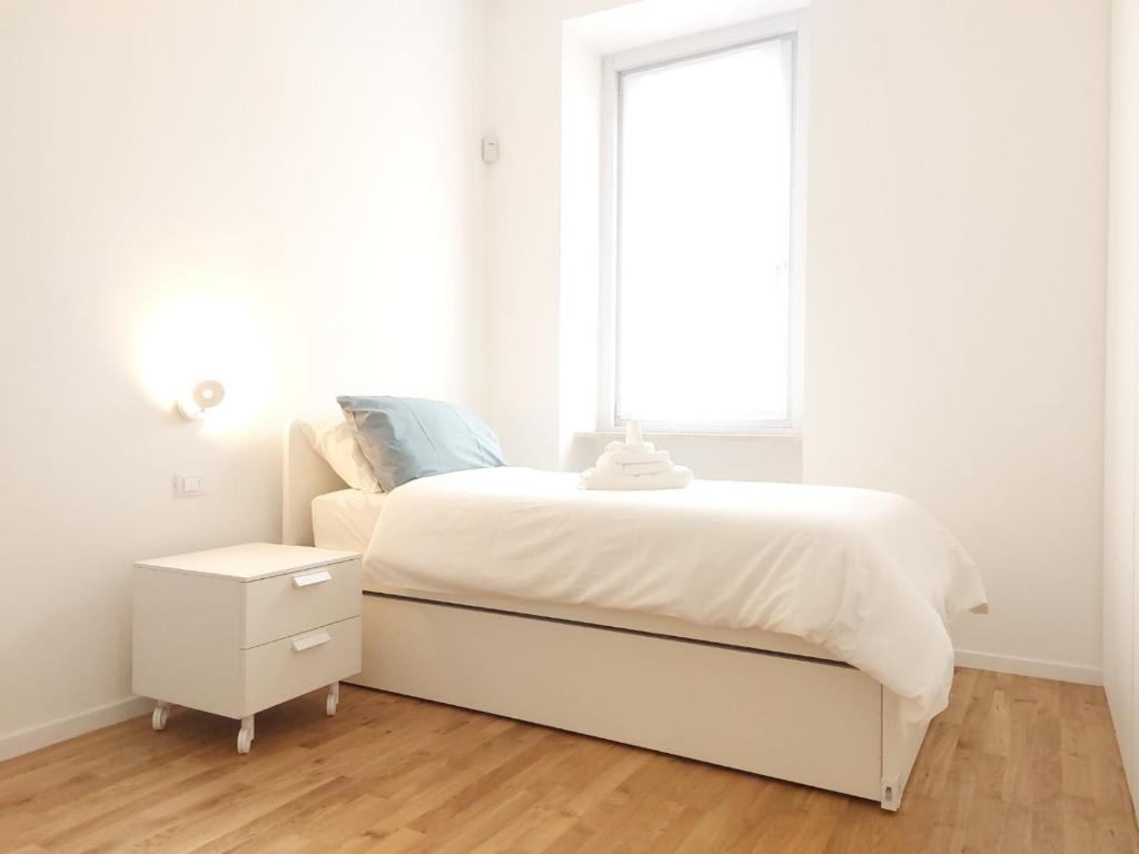 a white bedroom with a white bed and a window at Apartment Ca' de Bezzi in Bolzano