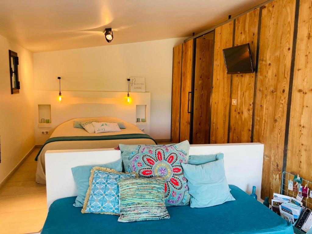 a bedroom with two beds and a couch with pillows at Le Nid de la Huppe in Noves