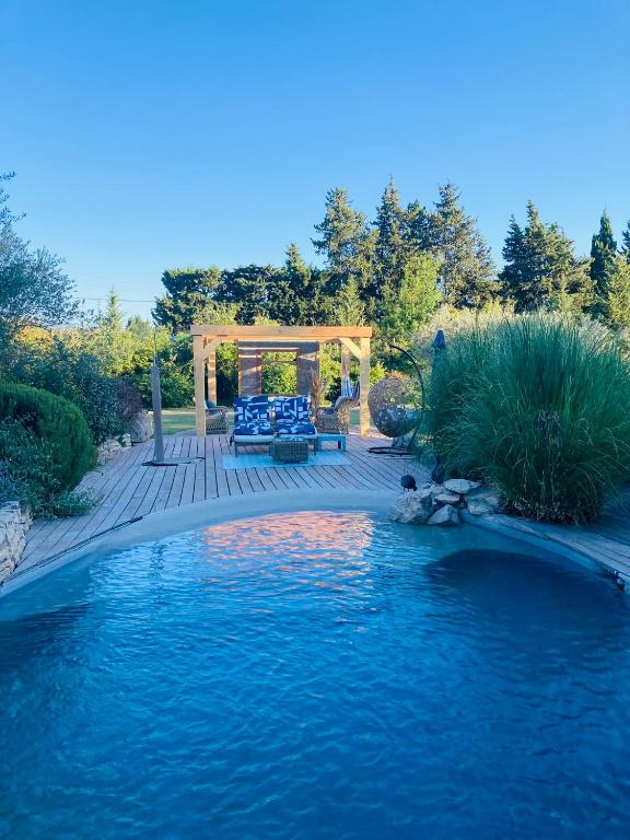 une terrasse en bois avec un banc et une piscine d'eau dans l'établissement Le Nid de la Huppe, à Noves