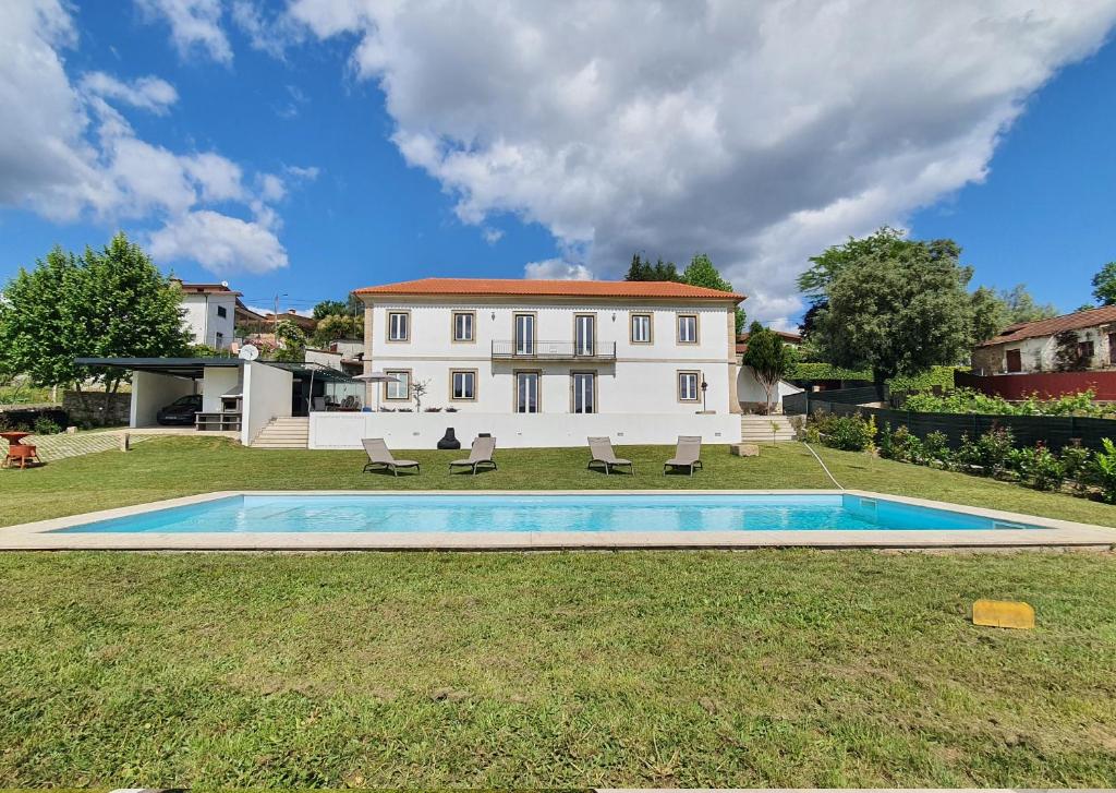 a villa with a swimming pool in front of a house at Casal Magister in Pedraça