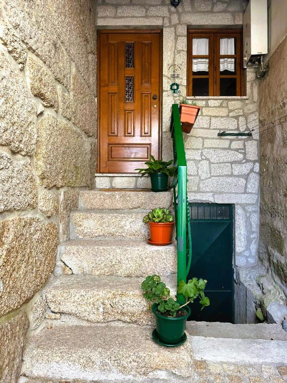 a front door of a stone house with potted plants at Casa do Palheiro in Campo do Gerês