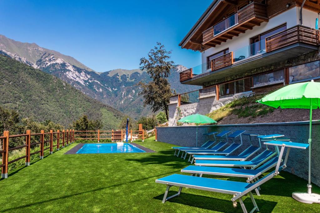 a resort with a swimming pool with chairs and umbrellas at Casa Panorama - Ledro House in Pieve Di Ledro