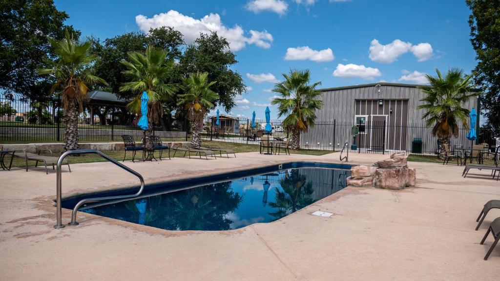 una piscina con sillas y árboles y un edificio en D&R Rivercity RV Resort en New Braunfels