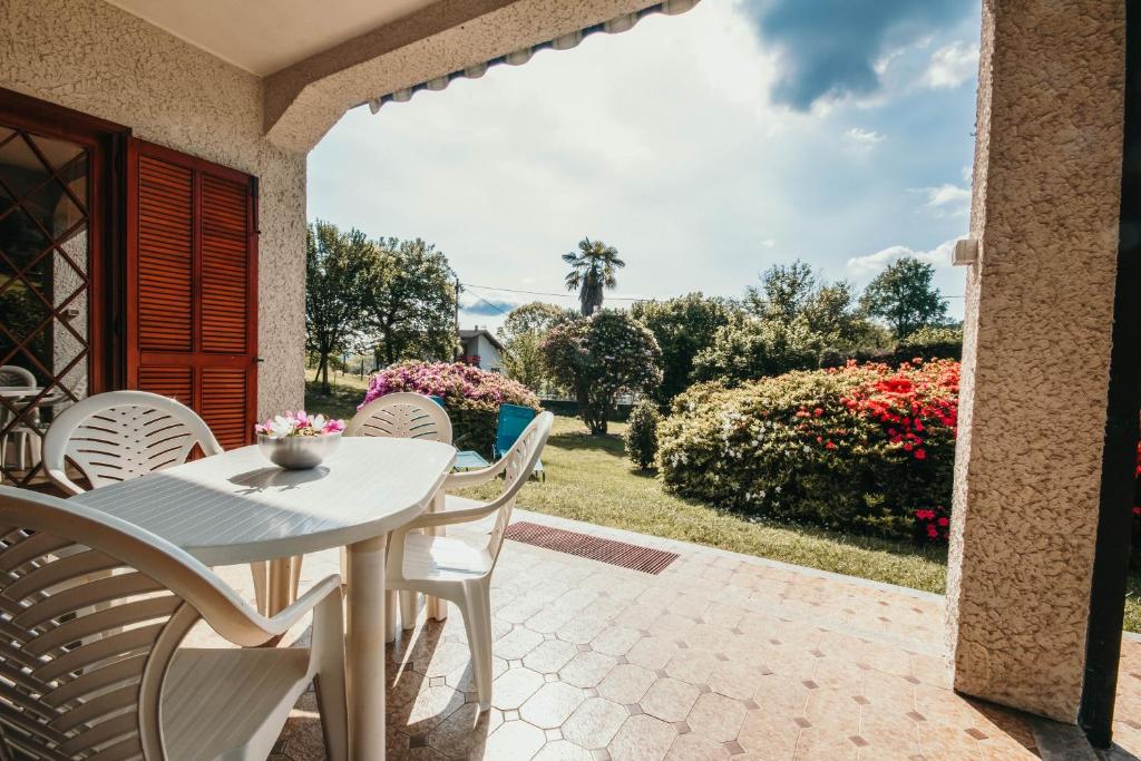 een patio met een witte tafel en stoelen en bloemen bij La Quiete - Lakeside Leisure & Business in Arona