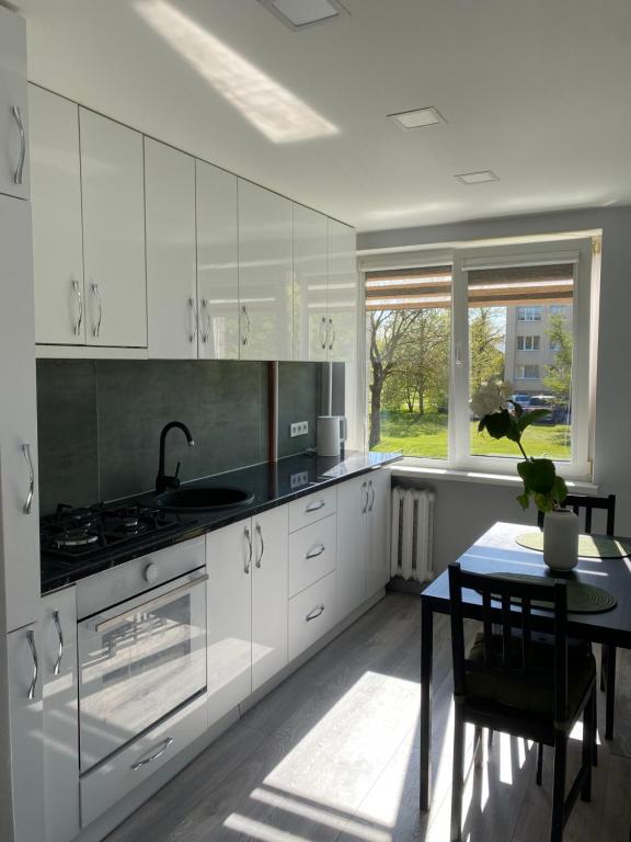uma cozinha com armários brancos, uma mesa e uma janela em 1 kambario butukas Kelmėje em Kelmė