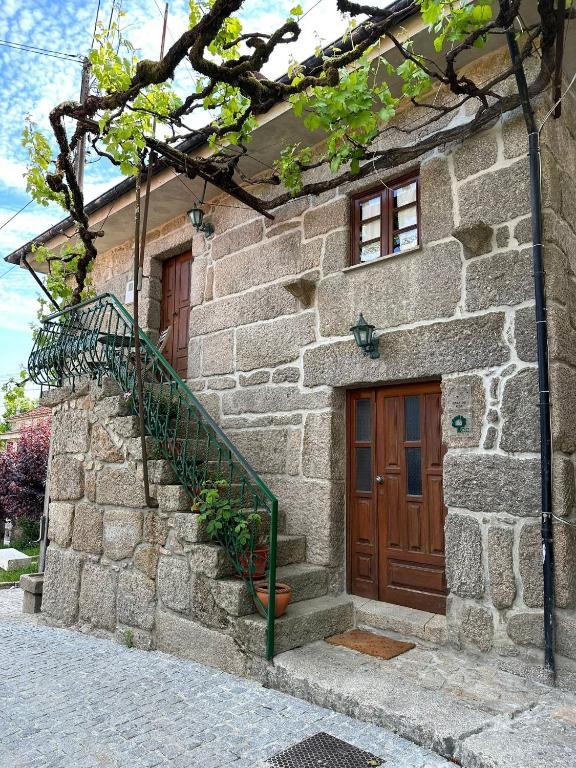 a stone house with a wooden door and stairs at Casa da Eira in Campo do Gerês