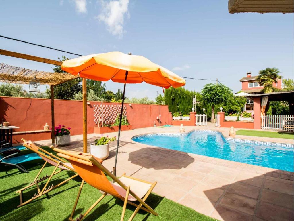 Parasol i krzesła obok basenu w obiekcie Casa El Rosal Blanco w mieście Padul