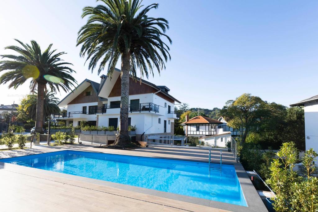 una piscina frente a una casa con palmeras en Ama Guadalupekoa, en Hondarribia