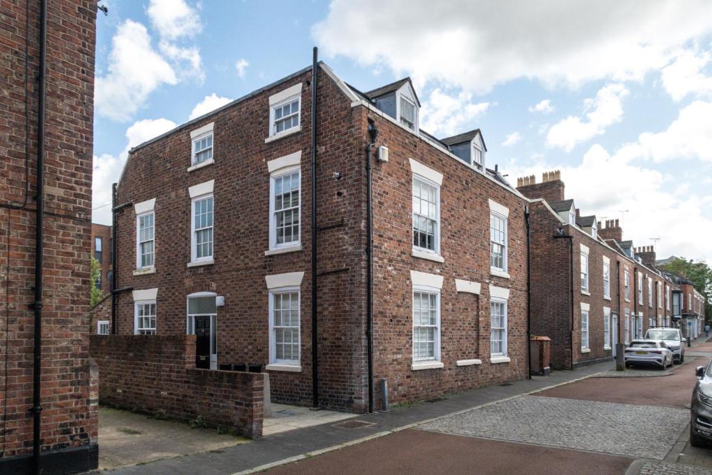 a red brick building with white windows on a street at Chester Stays - Beautiful loft apartment with parking in Chester