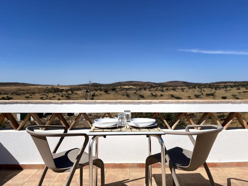 una mesa y sillas en un balcón con vistas en See You Again Mértola - Suites do Tamejoso, en Mértola