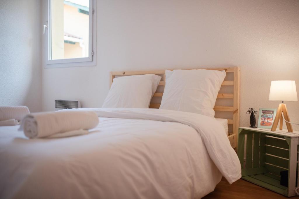 sypialnia z łóżkiem z białą pościelą i oknem w obiekcie Duplex familial proche plage et commerces w mieście Capbreton