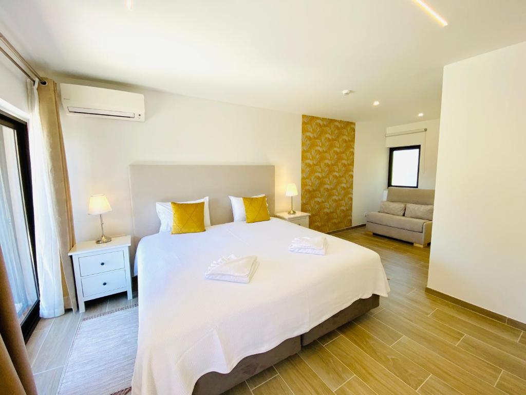 a bedroom with a large white bed with yellow pillows at Quinta das Andorinhas in Carvoeiro