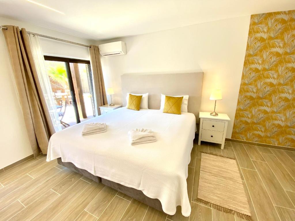 a bedroom with a large white bed and a window at Quinta das Andorinhas in Carvoeiro