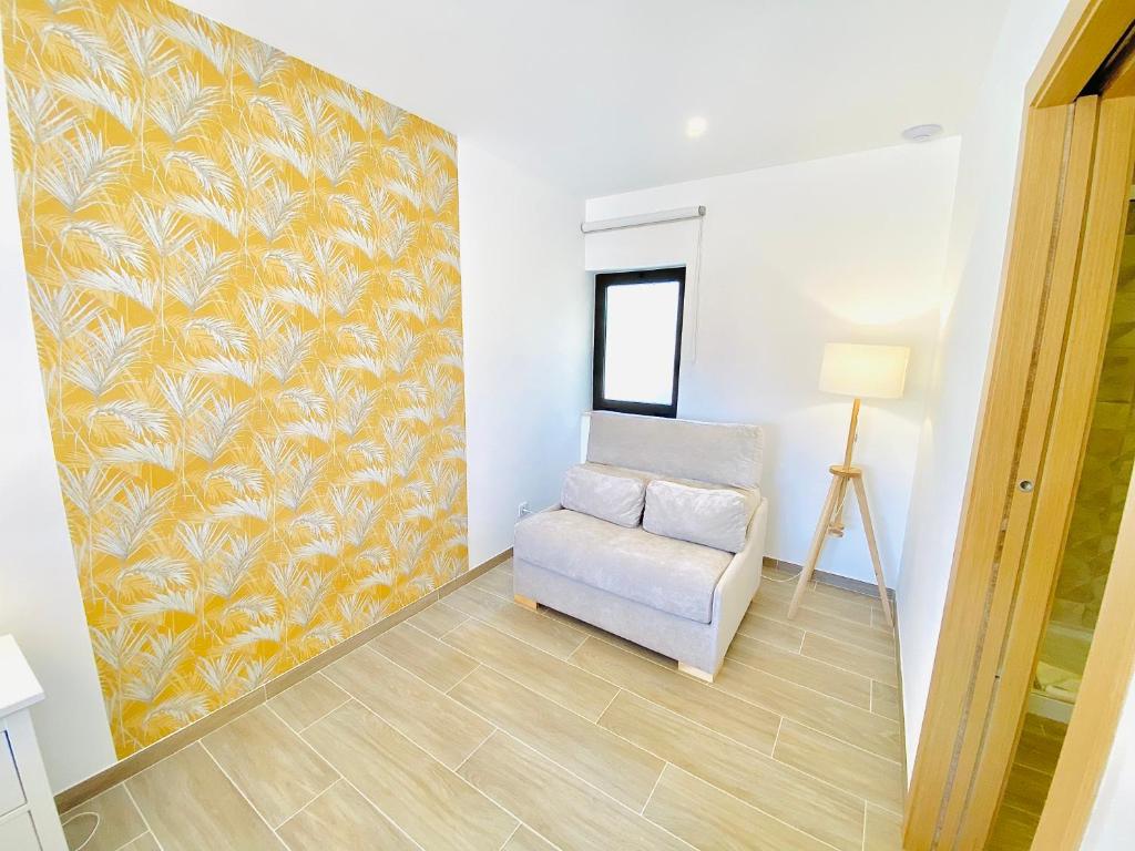 a living room with a chair and a wall at Quinta das Andorinhas in Carvoeiro