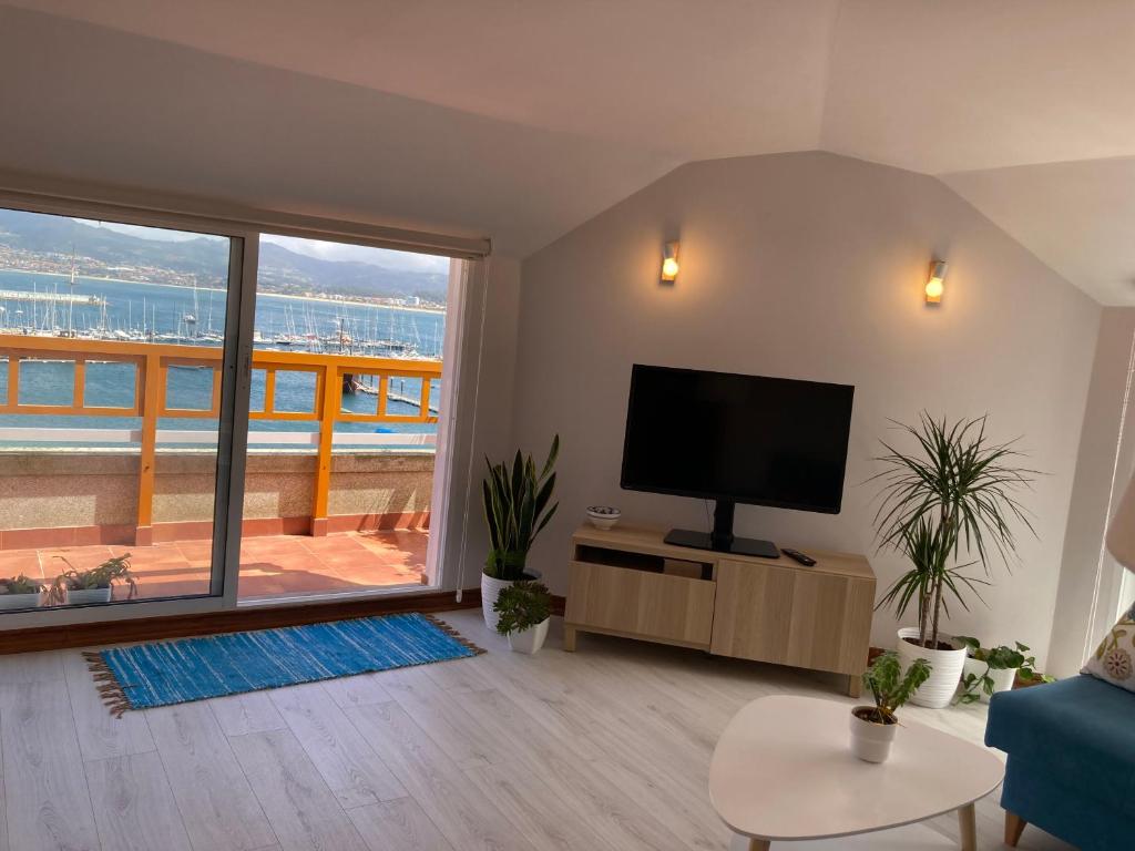 uma sala de estar com uma televisão e uma varanda em Exclusivo ático Baiona Carabela Pinta em Baiona