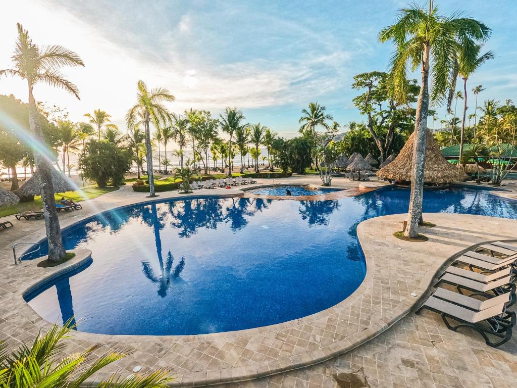 a large swimming pool with palm trees in a resort at Barceló Tambor - All Inclusive in Tambor