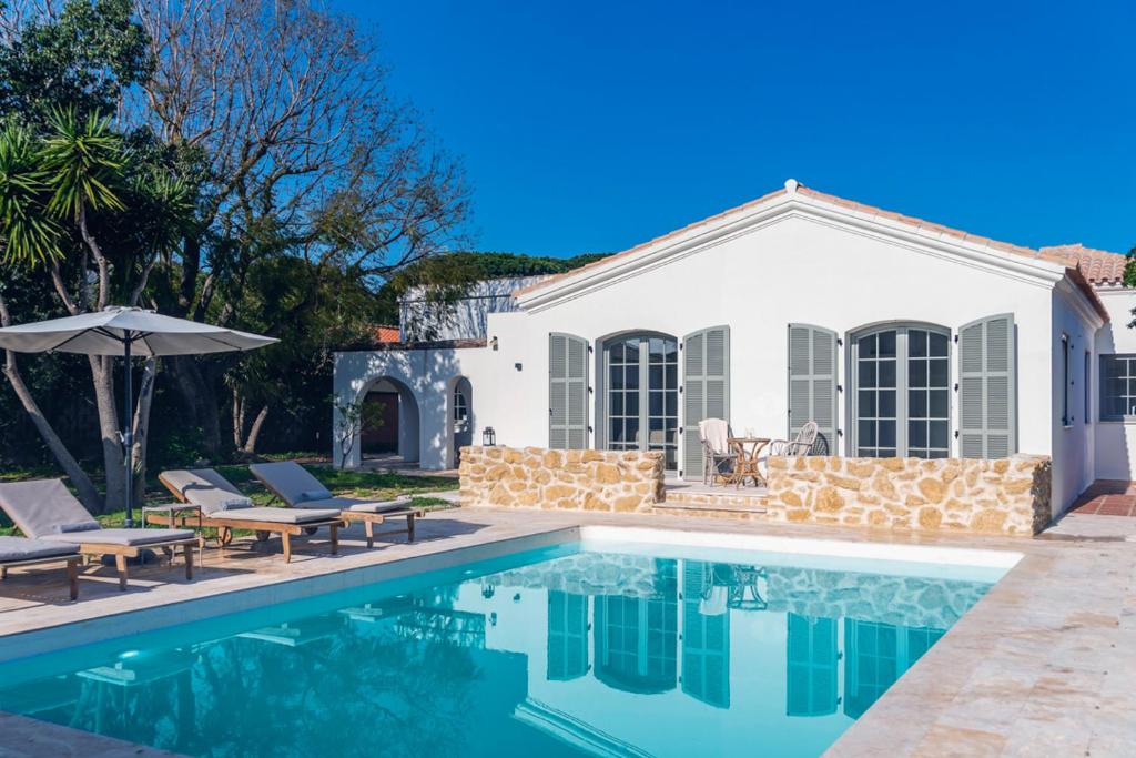 uma casa com uma piscina com cadeiras e um guarda-sol em ONLY FAMILIES Villa and Guest House with Private Pool em Chiclana de la Frontera