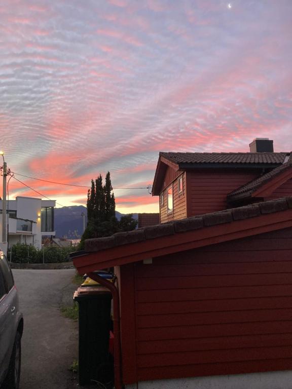 un edificio rosso con un tramonto sullo sfondo di Line på Hauane1 a Volda