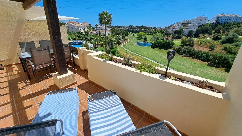 balkon z krzesłami i widokiem na pole golfowe w obiekcie Sunny Golf View Miraflores w mieście Sitio de Calahonda