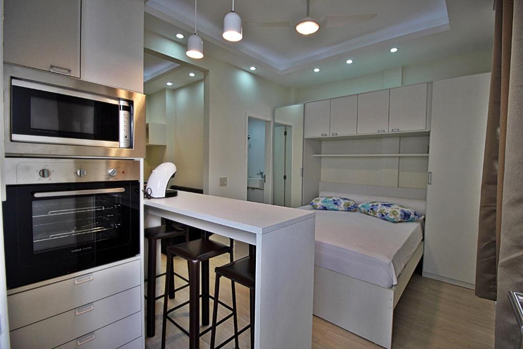 a white kitchen with a bed and a kitchen counter at Rio Spot Ipanema C011 in Rio de Janeiro