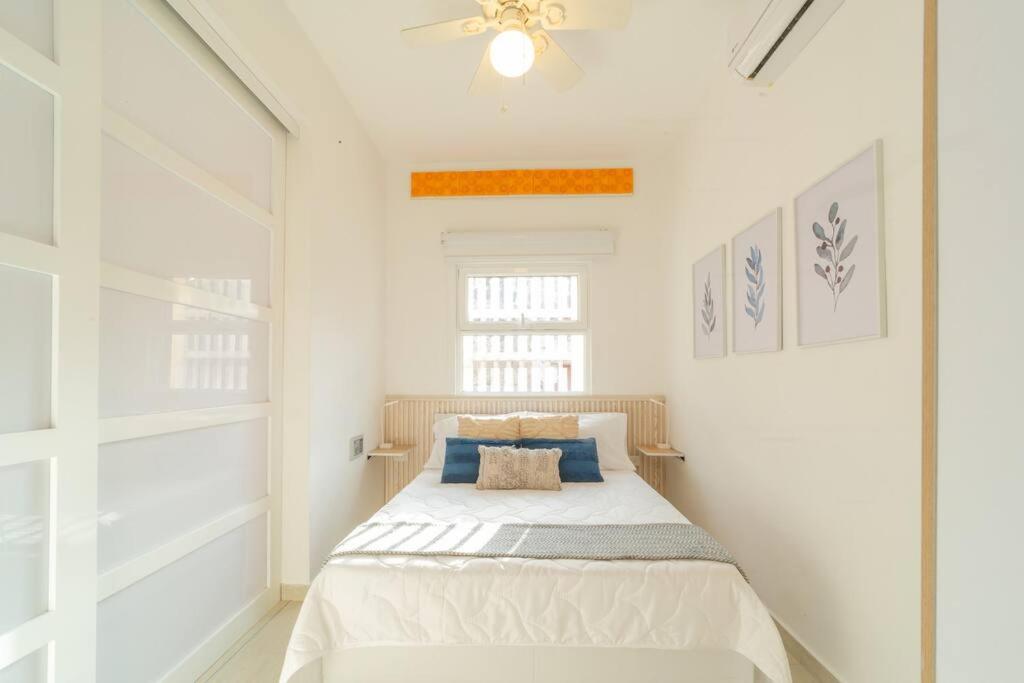 a white bedroom with a bed with blue pillows at C1-12 - Acogedor apartamento dentro de las murallas de Cartagena con aire acondicionado y agua caliente in Cartagena de Indias