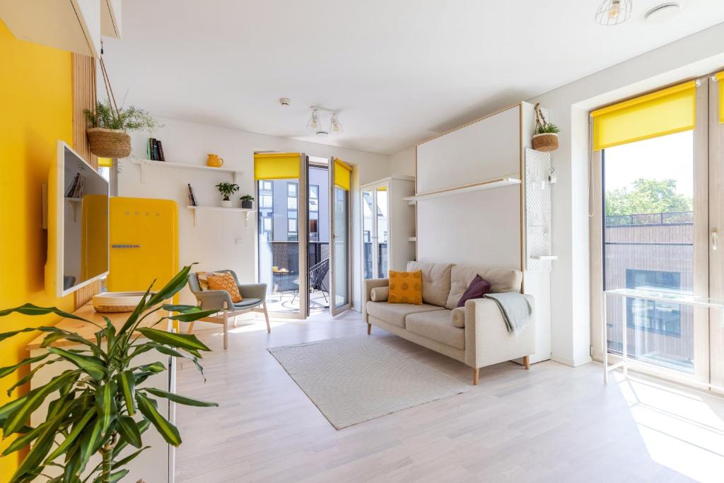 uma sala de estar com paredes amarelas e um sofá em Yellow Studio Paupys em Vilnius