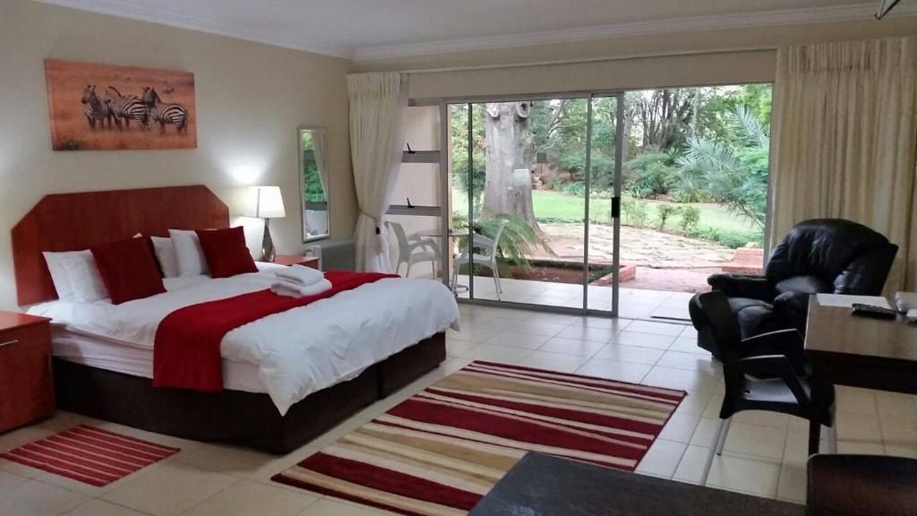 een slaapkamer met een groot bed en een groot raam bij Anka Lodge in Johannesburg