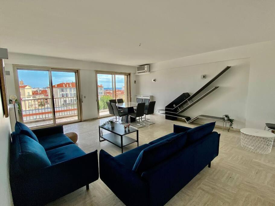 Central -300m Palais- Seaview-A/C-WIFI-spacieux في كان: غرفة معيشة مع أرائك زرقاء وطاولة