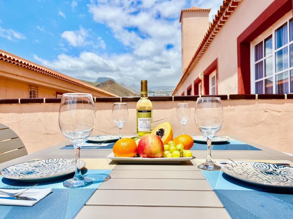 a table with a plate of fruit and a bottle of wine at !!! Relaxing View, The Heights Apartment With Terrace and Heated Pools, Los Cristianos in Los Cristianos