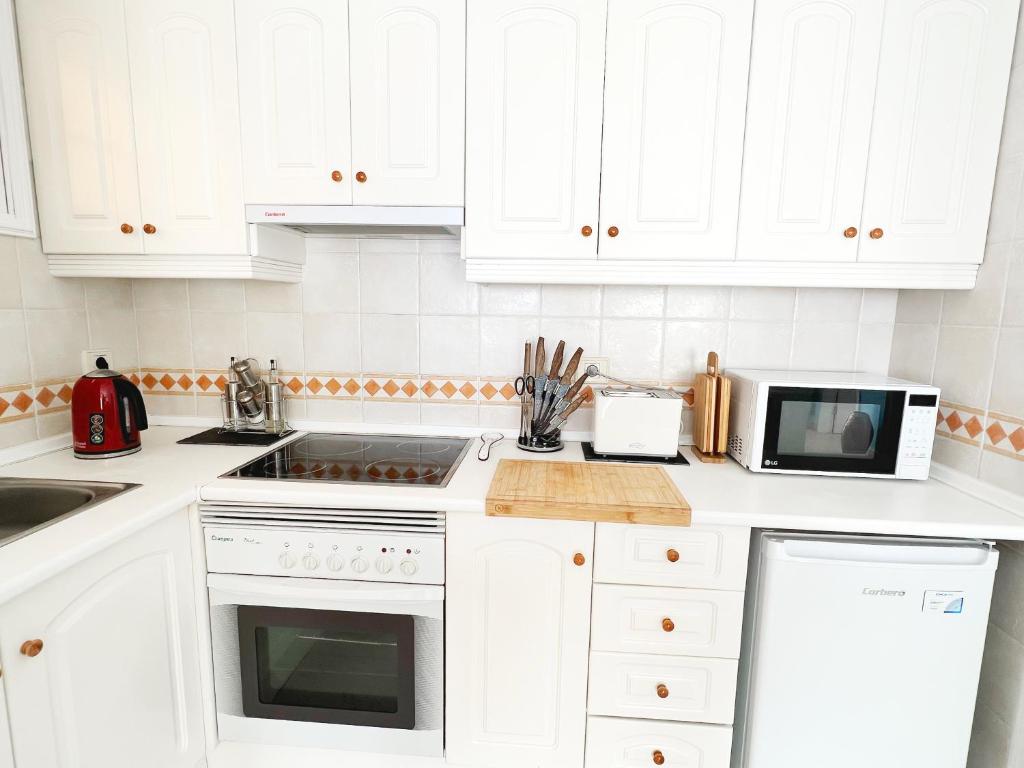a white kitchen with white cabinets and a microwave at !!! Relaxing View, The Heights Apartment With Terrace and Heated Pools, Los Cristianos in Los Cristianos
