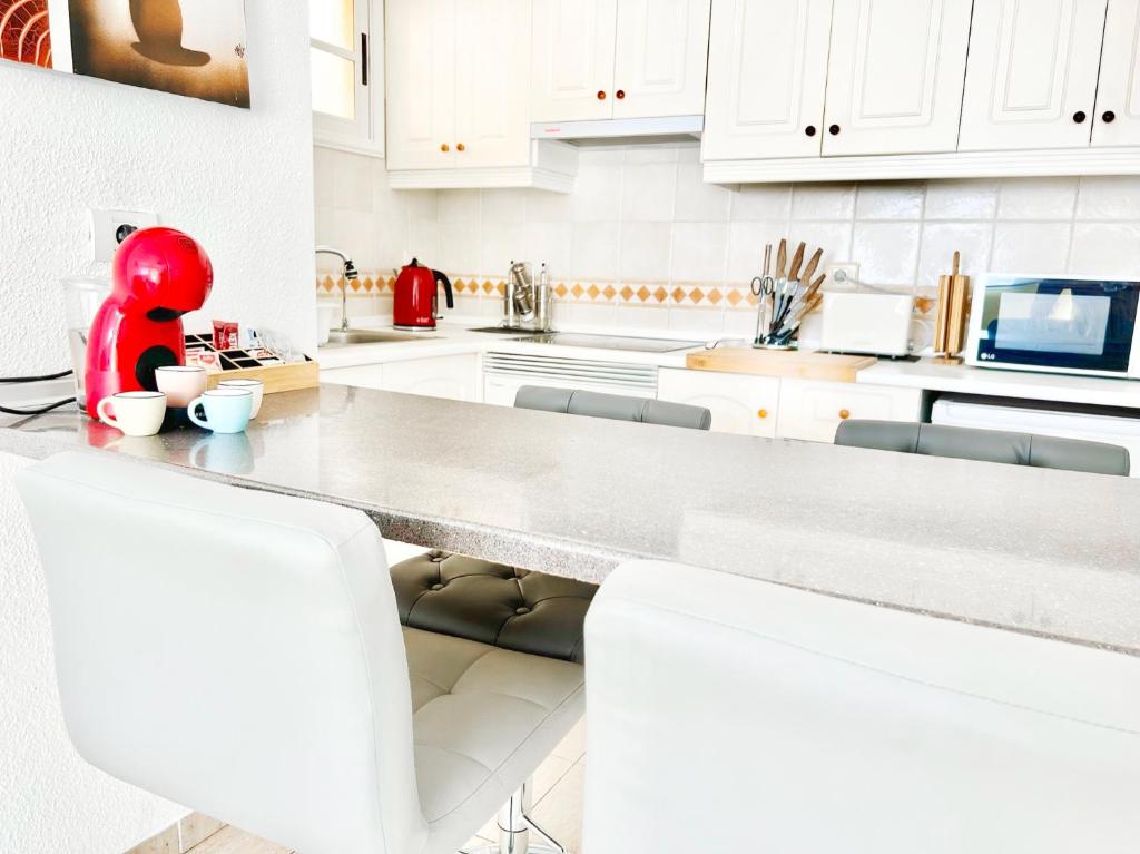 a kitchen with white cabinets and a red bear on a counter at !!! Relaxing View, The Heights Apartment With Terrace and Heated Pools, Los Cristianos in Los Cristianos