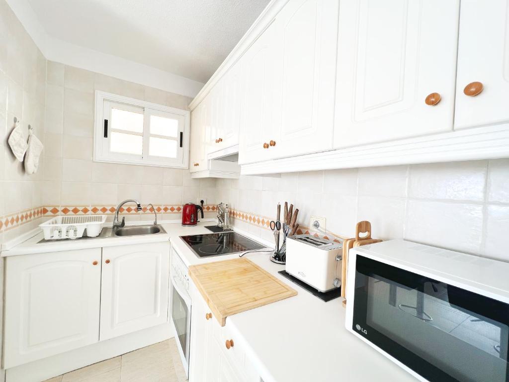 a white kitchen with white cabinets and a sink at !!! Relaxing View, The Heights Apartment With Terrace and Heated Pools, Los Cristianos in Los Cristianos