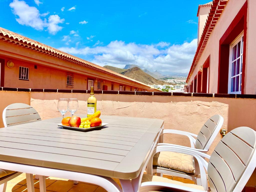 a white table with a plate of fruit and wine glasses at !!! Relaxing View, The Heights Apartment With Terrace and Heated Pools, Los Cristianos in Los Cristianos