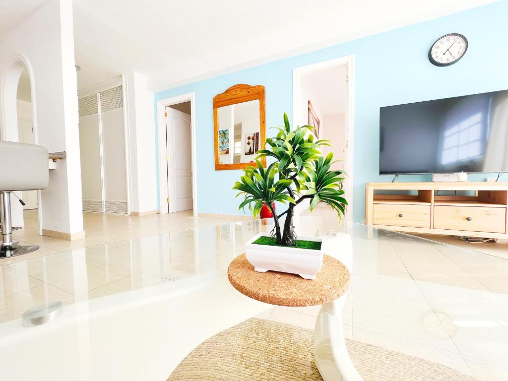 a living room with a tv and a potted plant at !!! Relaxing View, The Heights Apartment With Terrace and Heated Pools, Los Cristianos in Los Cristianos
