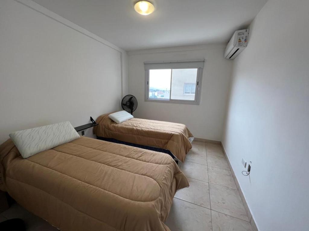 Habitación pequeña con 2 camas y ventana en Apartamento Ameghino en Salta
