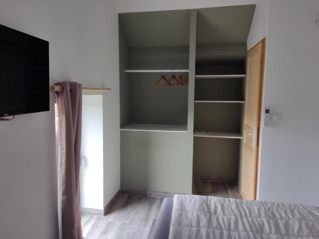 1 dormitorio con 1 cama, TV y estanterías en Les gîtes de Louise, en Archignac