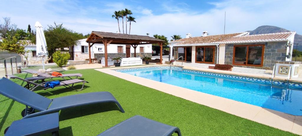 a swimming pool with chairs and a house at Casa Rancho Grande in Jávea