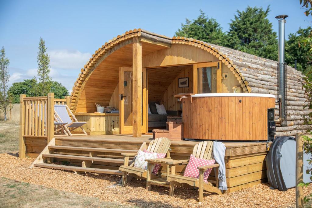 a log cabin with two chairs and a hot tub at Barnhorn Glamping in Hooe