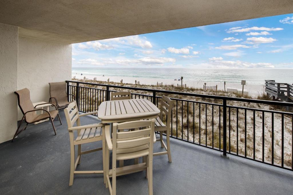 a balcony with a table and chairs and a view of the beach at Nautilus 1201 - Gulf Front 2 Bedroom Huge Wrap Around Balcony 2nd Floor! Free Beach Service 3/1-10/31 in Fort Walton Beach