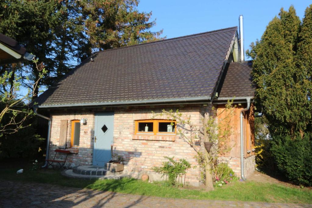 a small stone house with a black roof at Am Rieck - Ferienhaus "GR 1904" in Zempin