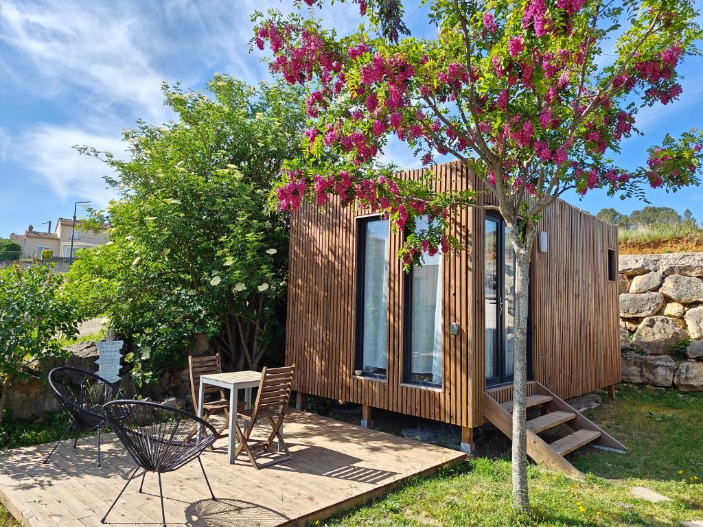 une petite cabane en bois avec un arbre et des fleurs roses dans l'établissement La Cabane de Lili Prune, à Goudargues