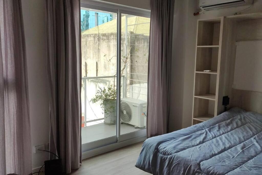 Dormitorio con cama y ventana con altavoz en Luminoso Monoambiente con Balcón al Frente Ciudad de la Paz y Rivera en Buenos Aires