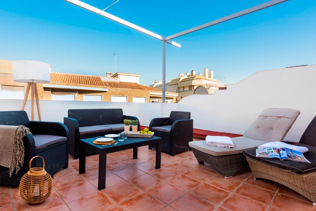 een patio met stoelen en tafels op een dak bij Genteel Home Ático Gran Capitán in Granada