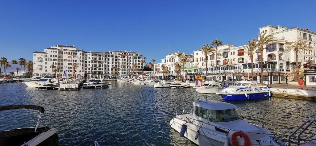 un groupe de bateaux amarrés dans un port avec des bâtiments dans l'établissement Puerto de la Duquesa Sea Views, à Manilva